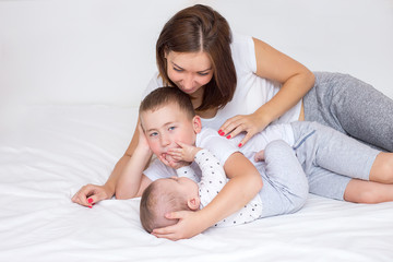 Young mom with her two sons playing on a bed