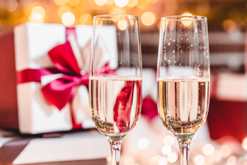 Two champagne glasses in front of christmas presents