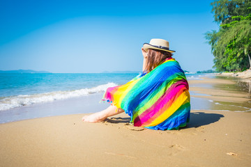 alone girl sitting on the beach with colorful scarf  