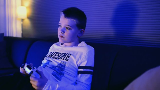 Close up of child playing video game and using a controller in living room