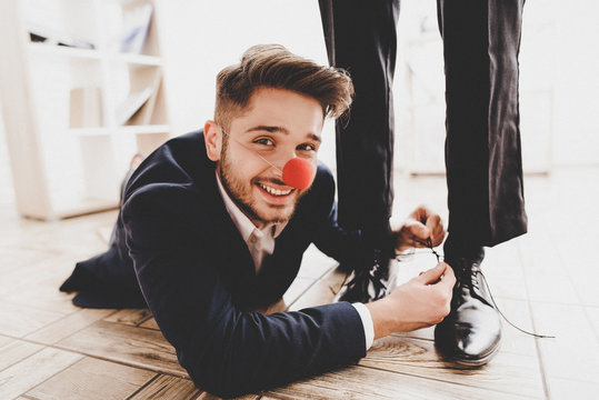 Man Lying on Floor and Tying Colleague's Shoelaces
