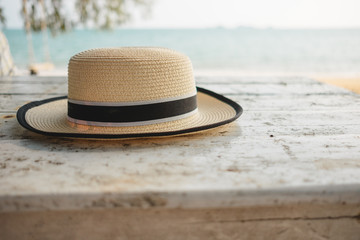 travel concept closeup sun hat placed on wood table by beach with sea background