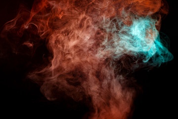 A background of blue, red and green wavy smoke in the shape of a ghost's head or a man of mystical appearance on a black isolated ground. Bright abstract pattern of steam from vape.