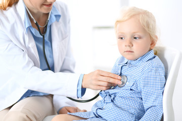 Doctor examining a little blonde girl with stethoscope.Medicine and healthcare concept