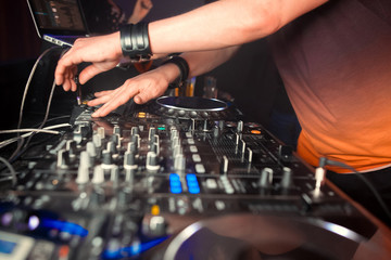 Dj mixes the track in the nightclub at party. In the background laser light show