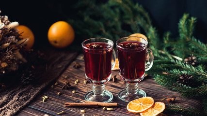 two glasses of mulled wine with spices and orange slices on a wooden table. Hot alcoholic drink on the background of Christmas decor