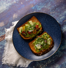 Delicious avocado toast with fresh vegetables on blue background