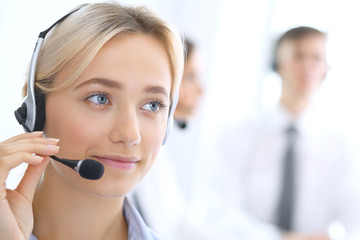 Call center. Group of operators at work. Focus at blonde business woman in headset