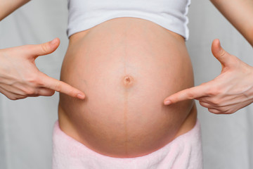 pregnant girl points her hands at her belly
