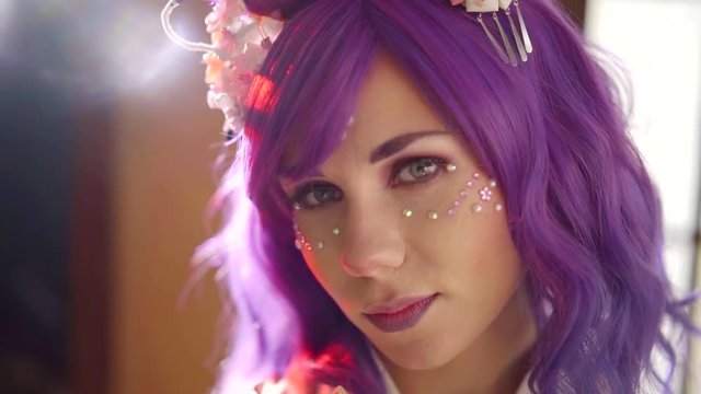 portrait of fashion model with purple hair and creative face art with crystals on skin, romantic
