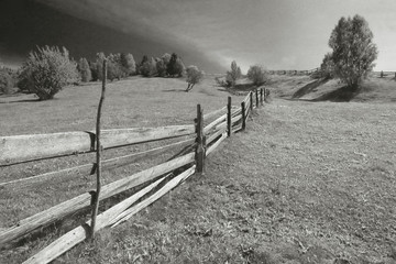 Long hill side wooden fence b&w