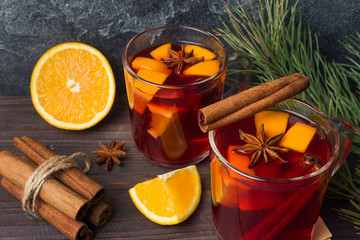 Christmas mulled red wine with spices and fruits on a wooden rustic table. Traditional hot drink at...