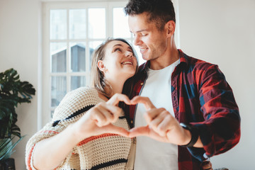Happy couple domestic life situation. Wife and husband in love making heart symbol with hands