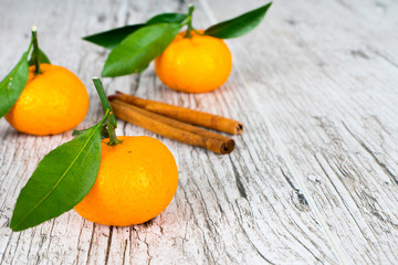 tangerines with leaves and cinnamon on wooden table
