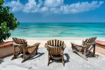 Fototapeta na wymiar Wooden beach chairs facing the clear tropical ocean