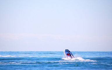 Man drives an inflatable rubber boat with a motor in the open sea.