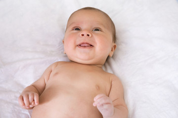 Close-up portrait of baby awake. Newborn baby lies on his back and tries to smile for the first time
