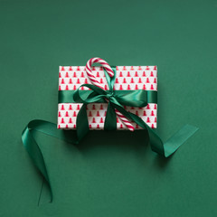 Christmas giftbox with candy cane on green surface. Xmas card. Top view.