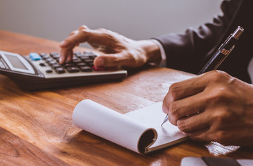 businessman hand using calculator Calculating bonus(Or other compensation) to employees to increase productivity.Writing paper on desk.Selective Focus