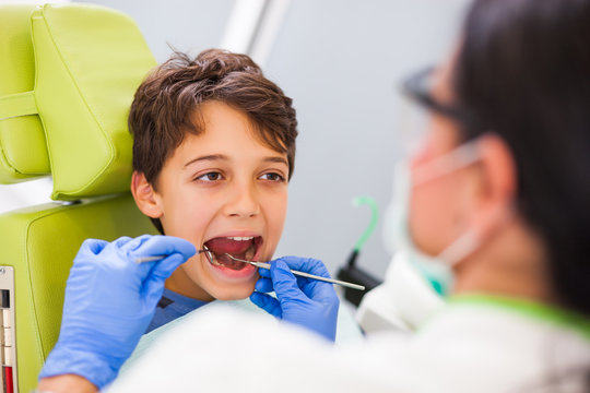 Dentist is examining teeth of a boy. 