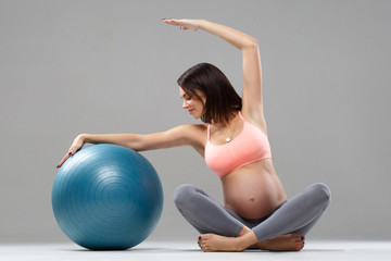 Fototapeta na wymiar Athletic pregnant woman goes in for sports with the ball.