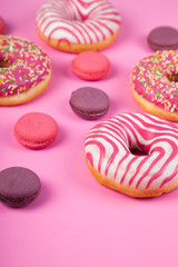 Donuts and macaroons on a pink background.