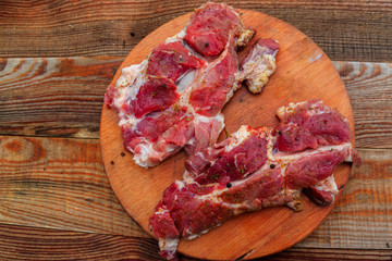 Fresh raw pork meat with spices on wooden cutting board on rustic table. Top view