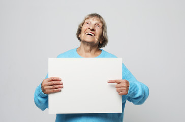 Aged woman with blank advertising board or copy spacet.