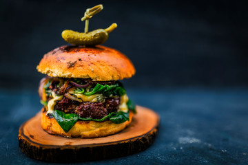Tasty grilled beef burger with spinach lettuce and blue cheese served on wooden table with...