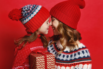 happy family mother and child daughter with christmas gifts on red background