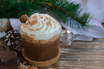  Cup of hot chocolate cocoa with whipped cream and chocolate crumbs on wooden table with  christmas decoration. Delicious cold weather beverage concept.