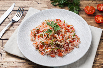 Rice with tomato sauce and greens on wooden background.