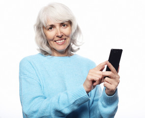 grandmother is talking to her grandchildren by phone, smiling and greeting them.