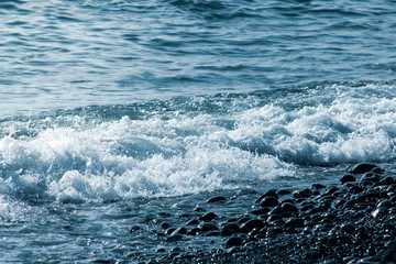Abstract texture of the colored stones and waves on the beach.