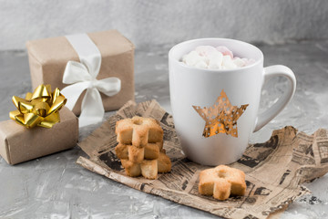 winter hot sweet drink cup with gift boxes and cookies on a shabby gray concrete background