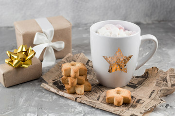 Obraz na płótnie Canvas winter hot sweet drink cup with gift boxes and cookies on a shabby gray concrete background