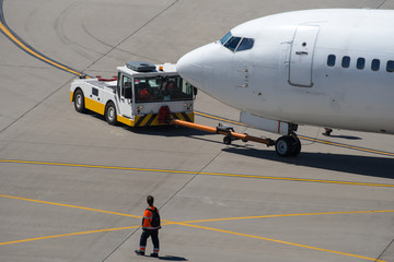 Modern twin engine civil airplane pushing back at international airport