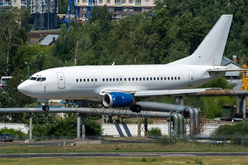 White modern twin engine passenger airplane landing at international airport
