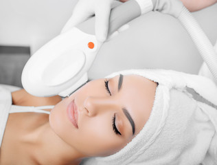 woman receiving procedure, skin rejuvenation at beauty salon. Elos procedure removes brown spots...