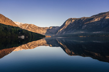 Sunrise view of alpine lake Bohinj with blue sky, sunlight and mist over water. Circles in water. Famous lake of Bohinj in Triglav National Park, Julian alps, Slovenia.