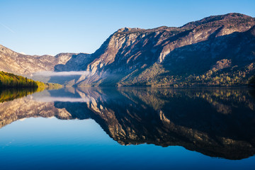 Sunrise view of alpine lake Bohinj with blue sky, sunlight and mist over water. Circles in water. Famous lake of Bohinj in Triglav National Park, Julian alps, Slovenia.