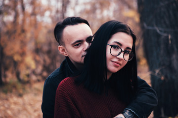 young man and young woman are sitting on a plaid in an autumn forest