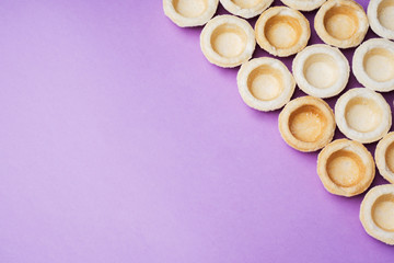 Empty shortbread tartlets laid out in a row. Abstraction concept in the color of the surface Copy space