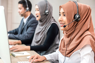 Beautiful Asian muslim woman working  in call center with team