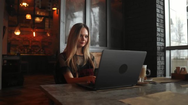 Happy young woman drinking coffee and using tablet computer in cafe