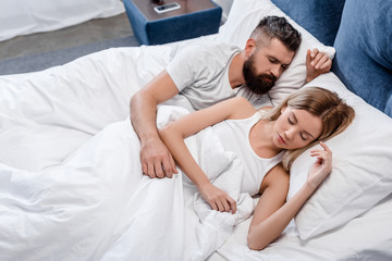 Young couple sleeping in bright bedroom in morning