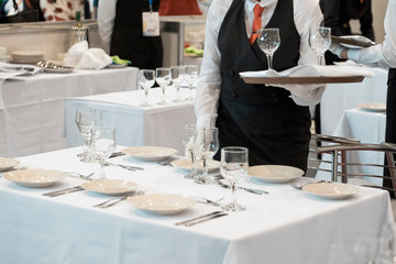Waitress dressed in the uniform serving a set of wine glasses