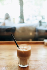Fragrant fresh ice coffee on the table inside the cafe next to the window. Morning refreshing soft drink.