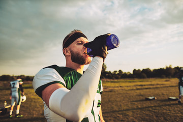 American football player drinking water during a team practice
