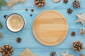 Christmas composition with round wooden tray or cutting board. Coffee cup, rope, anise star, gift and cones on wooden blue background. Winter, christmas concept. Flat lay, top view mock-up